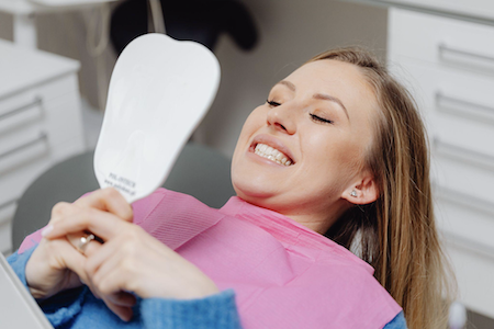 woman smiling into handheld mirror