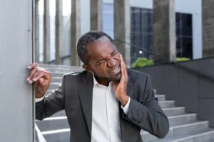 man in a business park suffering from severe tooth pain, possible dental emergency