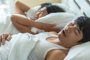 man suffering from snoring, disrupting his partners sleep