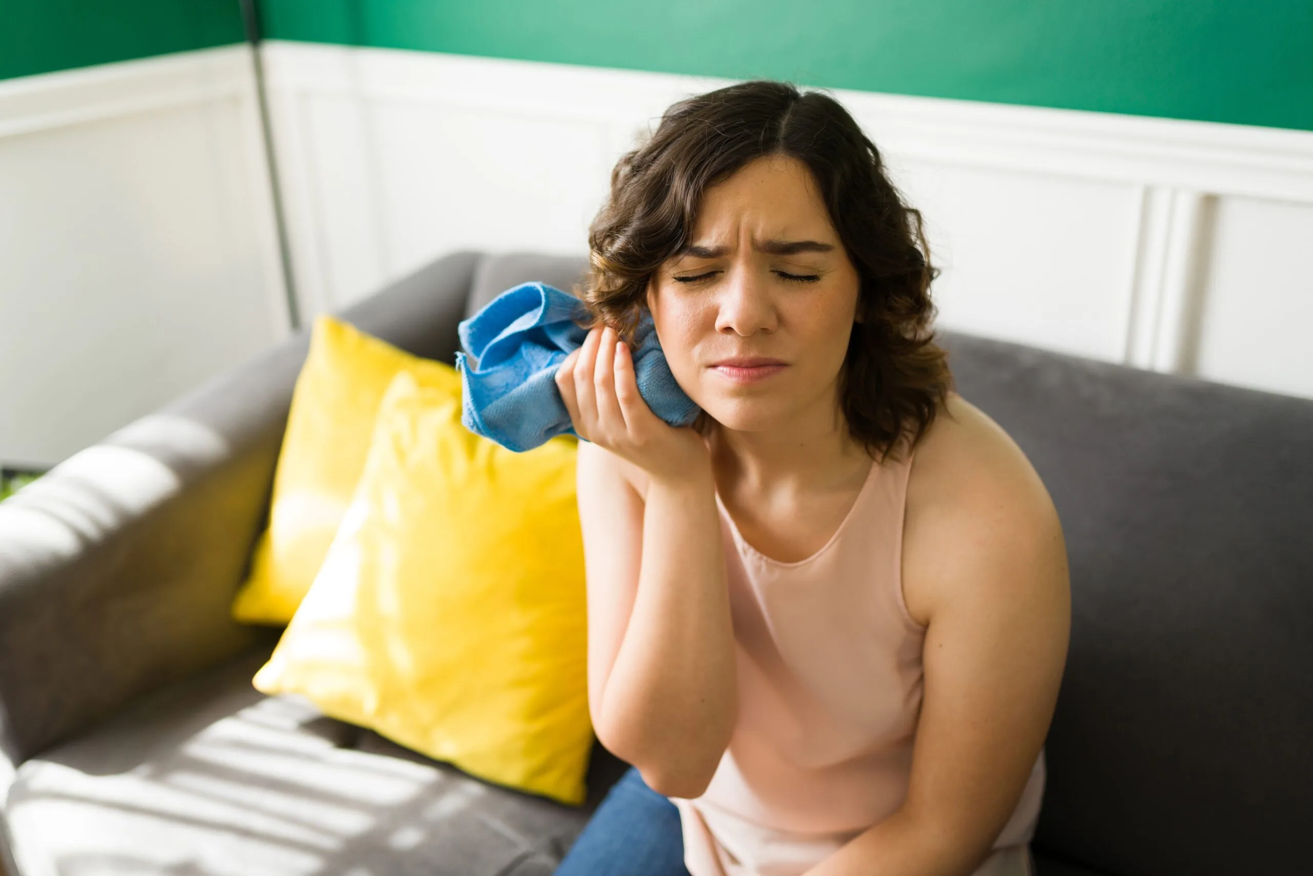 young woman with an ice pack on her jaw, possible damaged veneer
