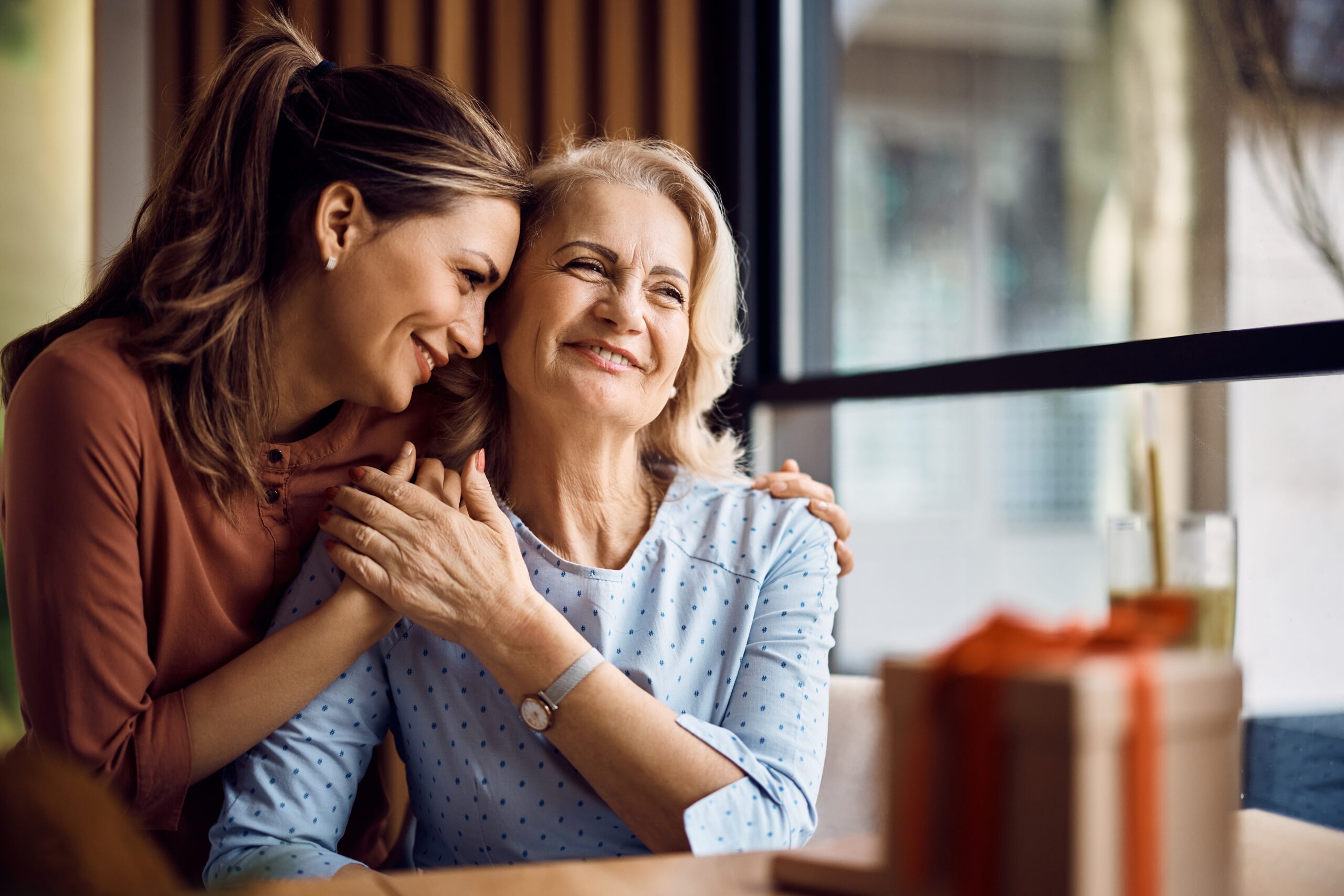 older woman with her daughter, hugging and smiling