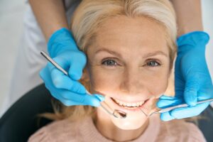closeup of a dentist in blue gloves working on a female patients bridge