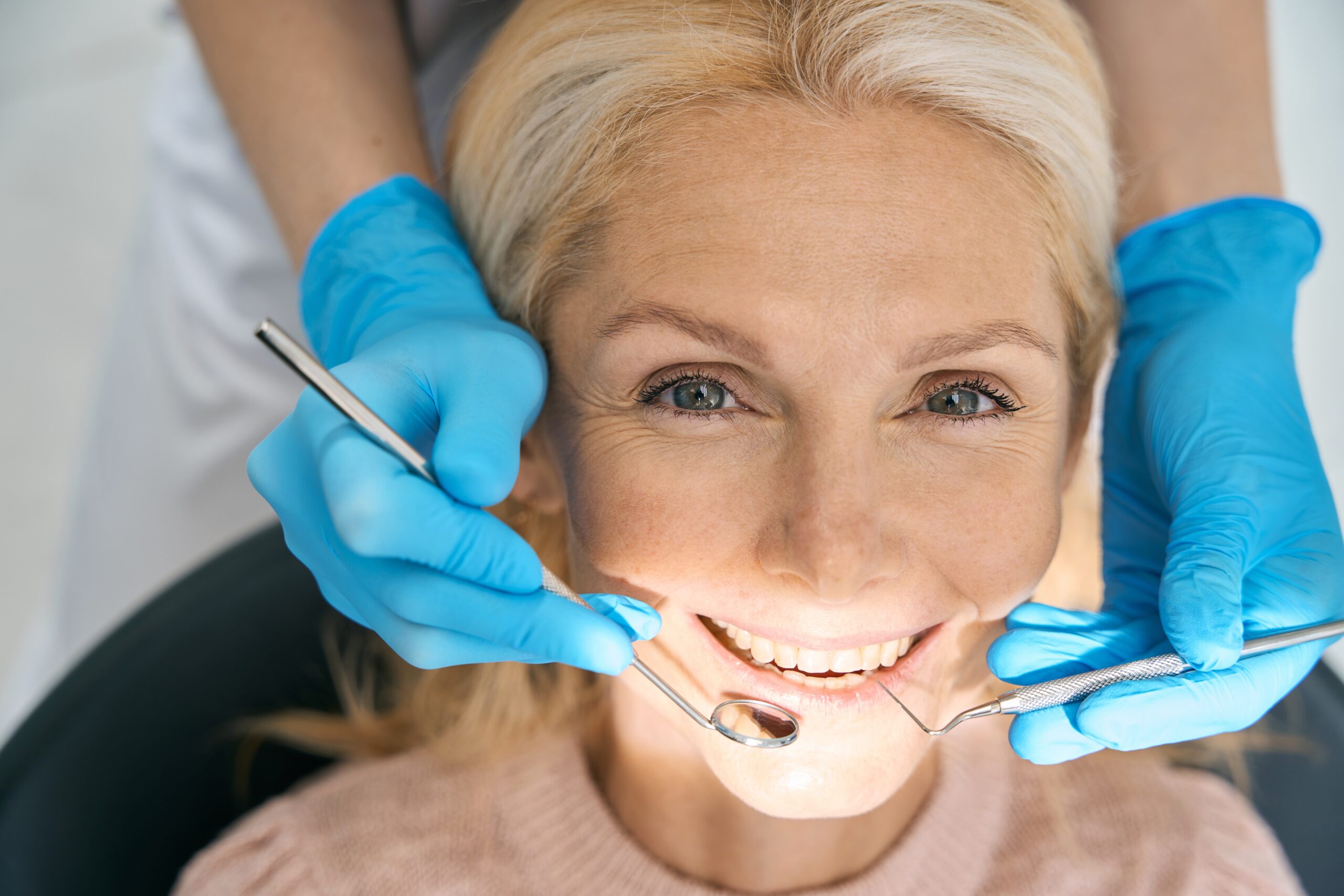 closeup of a dentist in blue gloves working on a female patients bridge