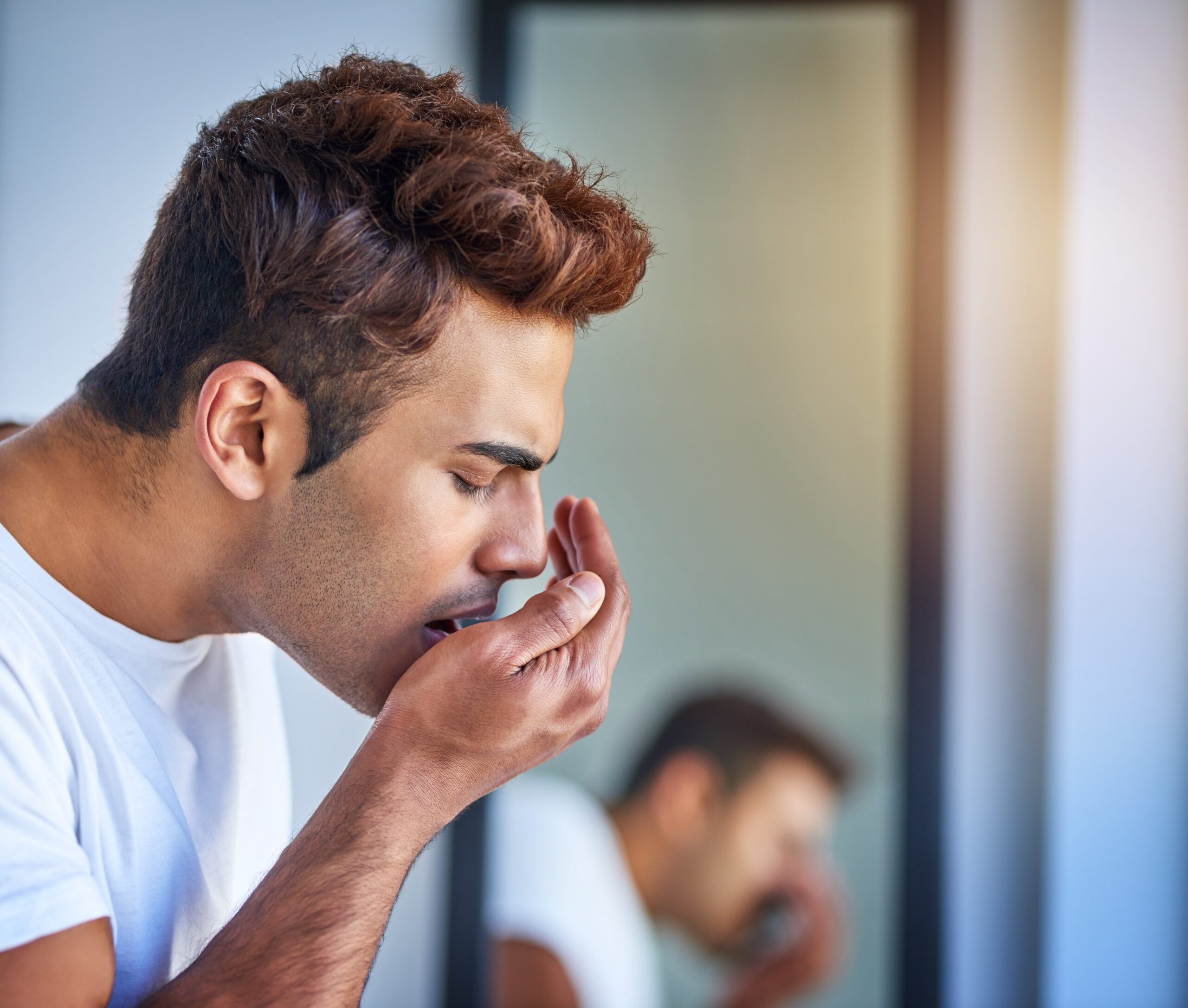 young man blowing into his hand checking for bad breath