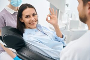 calm young woman flashing the ok sign sitting in dental chair